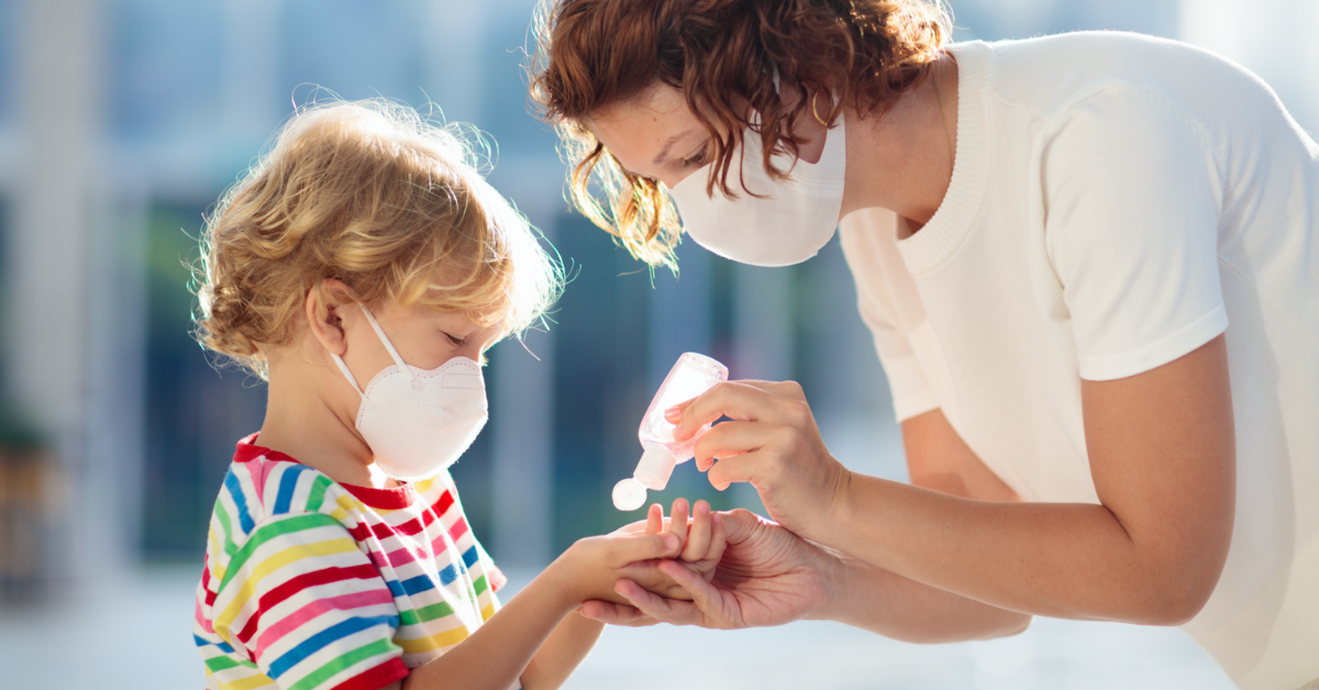 Mother and child in face masks applying hand sanitizer