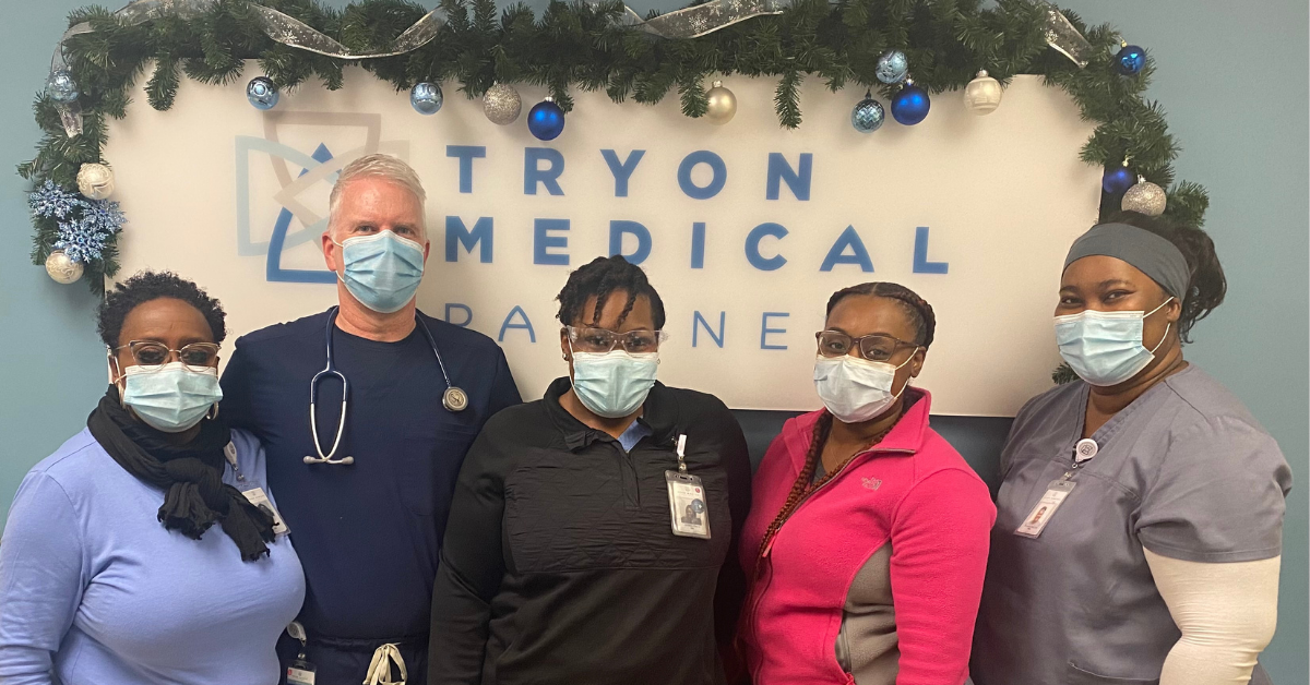Tryon Medical Partners team members wear masks and pose with holiday decor
