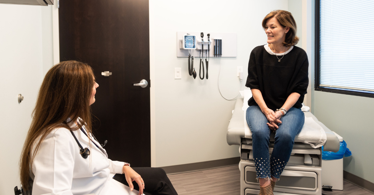 Female physician talks with female patient in exam room - Tryon Medical Partners