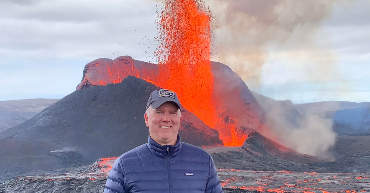Dr. Carl Hughes stand in front of an active volcano in Iceland