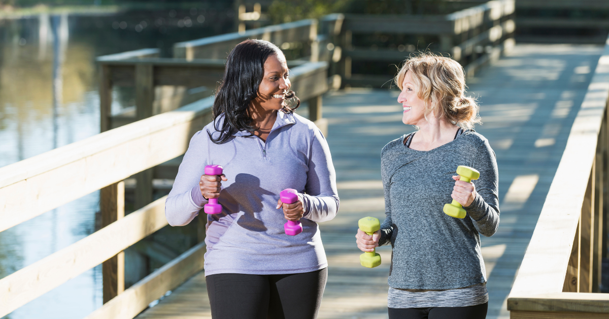 Two women walking in a park with weights