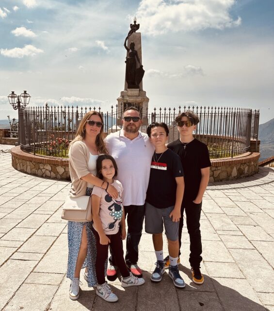 Stacie and Anthony Farinella are pictured on vacation standing with their three children